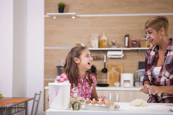 Young mother and her teenage daughhter playing with flour while making delicious food. — Stock Photo, Image