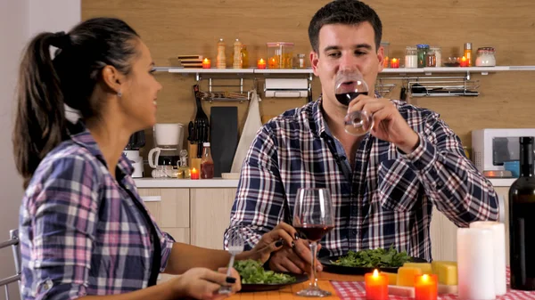 Schönes junges Paar genießt etwas Rotwein, während sie ein romantisches Abendessen genießen — Stockfoto