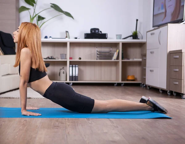 Ragazza bionda che fa cobra yoga posa nella sua casa — Foto Stock