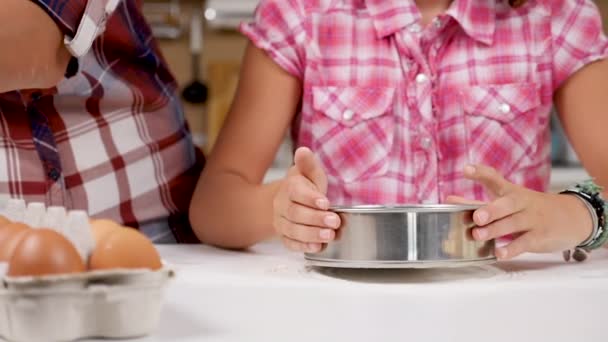 W kuchni córka sifts mąkę przez sito — Wideo stockowe