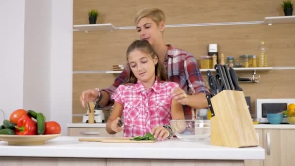 Junge Tochter schneidet eine Gurke, während die Mutter ihr hilft — Stockvideo