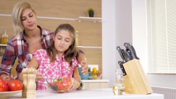 Madre cariñosa ayuda a su hija a mezclar una ensalada — Vídeo de stock