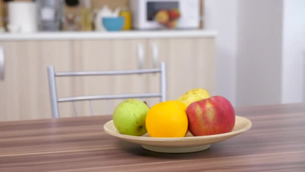 Свежие фрукты в деревянной тарелке на столе — стоковое видео