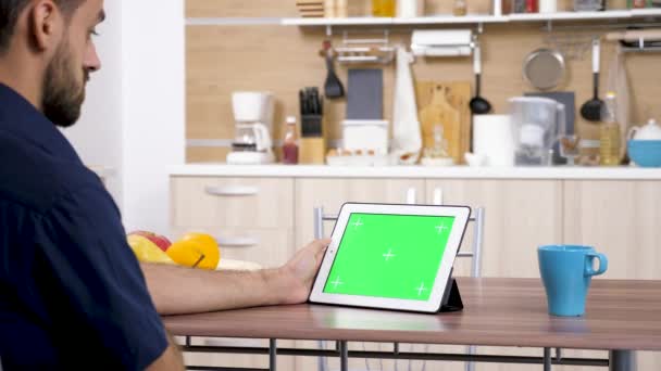 Человек на кухне смотрит на цифровой планшетный компьютер — стоковое видео