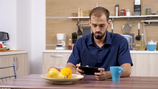 Homem usando um smartphone na cozinha — Vídeo de Stock