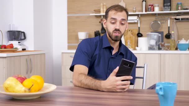 Un uomo in cucina che parla con qualcuno al telefono — Video Stock