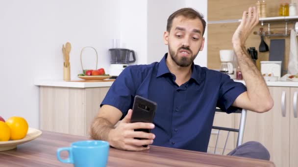 Un uomo in cucina che parla con qualcuno al telefono — Video Stock