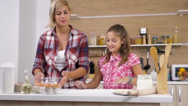 Mulher quebra um ovo enquanto sua filha brinca com a farinha — Vídeo de Stock