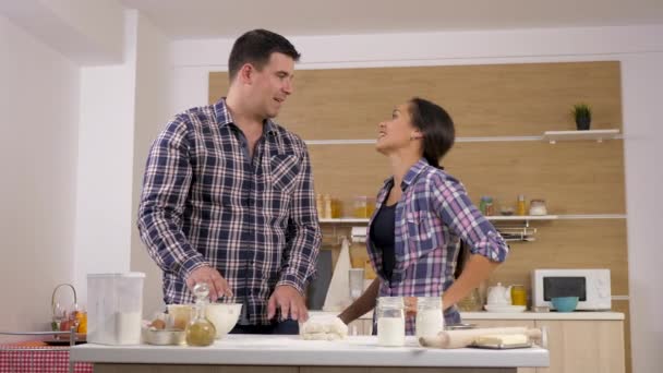 Feliz pareja sonriente jugando unos con otros en la cocina — Vídeos de Stock
