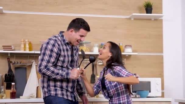 Feliz casal engraçado cantando em grandes colheres de plástico — Vídeo de Stock