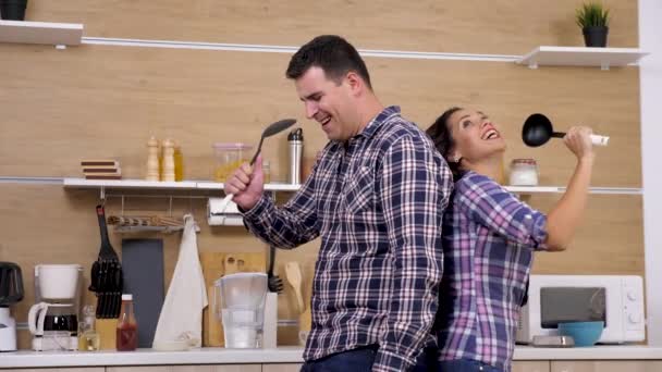 Feliz pareja positiva en la cocina cantando — Vídeos de Stock