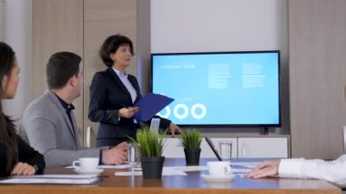 Toplantı salonunun önünde büyük ekran Tv animasyon veri ve grafikler ile içinde iş kadını. Dolly kaymak 4k görüntüleri