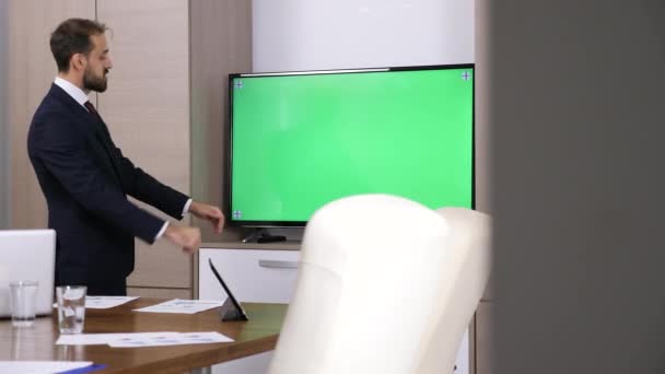 Revelador tiro de hombre de negocios hablando delante de la televisión de pantalla verde — Vídeo de stock