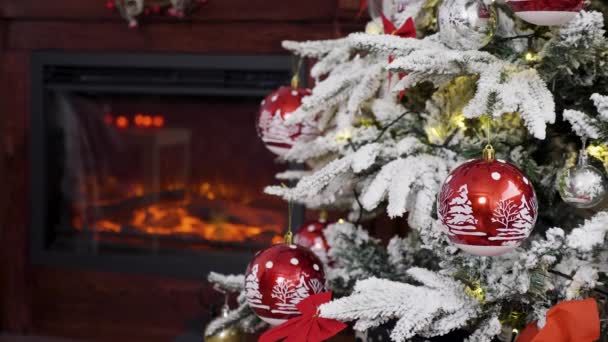 Arbre de Noël blanc avec des boules rouges dessus et une cheminée avec feu flou en arrière-plan 