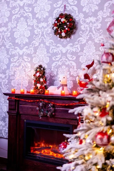 Díszített karácsonyfa előtt a kandalló mellett, a különböző gyertyák. — Stock Fotó