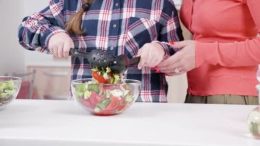 Kızı annesinin yanında salata karıştırma