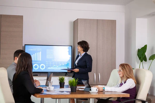 Empresarios y empresarios exitosos en la sala de conferencias analizando gráficos y diagramas en un televisor — Foto de Stock