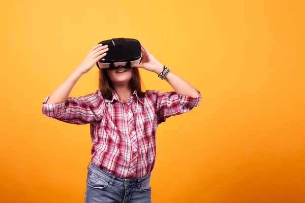 Niña tonteando con su VR sobre fondo amarillo en estudio — Foto de Stock