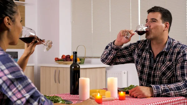 Красива молода пара насолоджується червоним вином, а їхня романтична вечеря — стокове фото