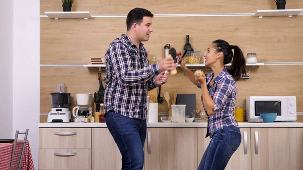 Young couple playing with kitchen tools while dinner gets ready — Stock Photo, Image