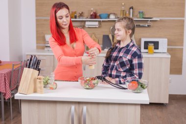 Küçük kız annesi onların mutfakta yemek yaparken yardımcı .