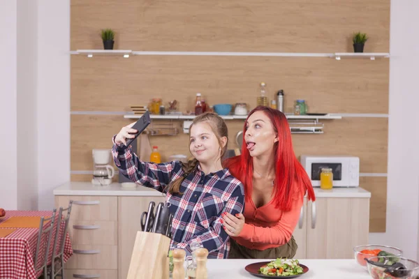 Kleines Mädchen makinf lustige Gesichter beim Kochen und Fotografieren — Stockfoto