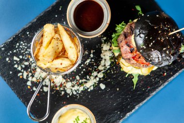 Biftek ve patates kızartması ile siyah burger içinde lezzetli peynir
