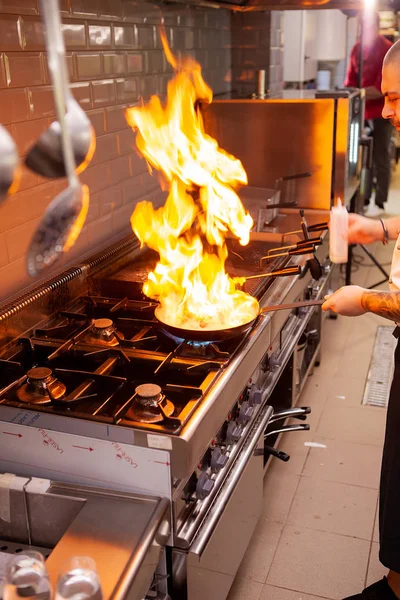O chef prepara o prato no fogão com uma fogueira aberta — Fotografia de Stock