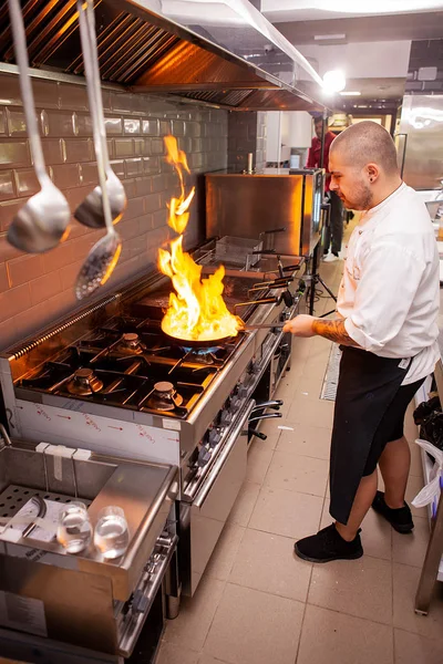 O chef prepara o prato no fogão com uma fogueira aberta — Fotografia de Stock