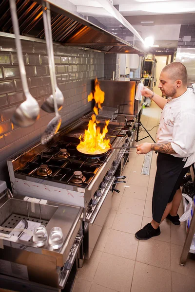 Chef cozinhar com chama em uma frigideira em um fogão de cozinha. — Fotografia de Stock