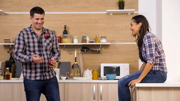 Husband juggles with apples for his wife while having dinner.