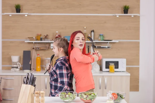Liten flicka som sjunger med mamma medan matlagning — Stockfoto
