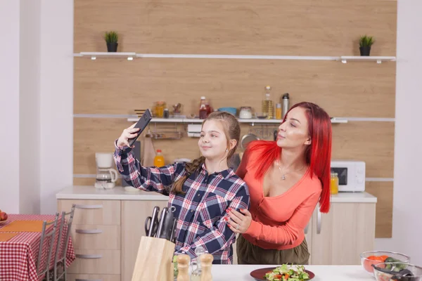 Kleines Mädchen makinf lustige Gesichter beim Kochen und Fotografieren — Stockfoto