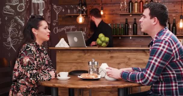 クロワッサンを食べると、スタイリッシュなコーヒー ショップ レストラン パブでコーヒーを飲みながら美しいカップル — ストック動画