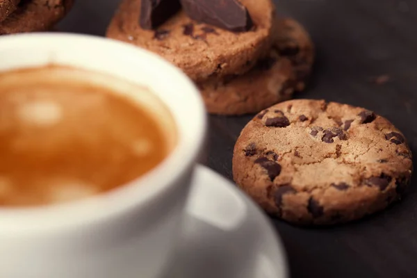 Biscoitos caseiros de chocolate e uma xícara de café na velha mesa de madeira escura . — Fotografia de Stock