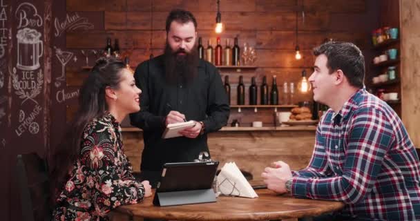 Bearded waiter taking order from a couple — Stockvideo