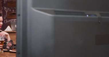 Drinking beer, eating peanuts and watching a game on TV in a vintage pub