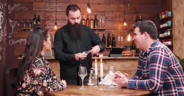 Bärtiger Hipster-Kellner öffnet eine Flasche Wein — Stockvideo