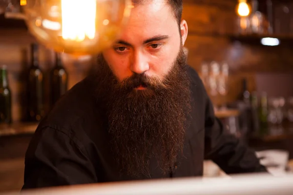 Stilig bartender kontrollera order på sin laptop. — Stockfoto