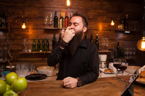 Bartende comiendo deliciosa manzana verde detrás del mostrador de la barra . —  Fotos de Stock