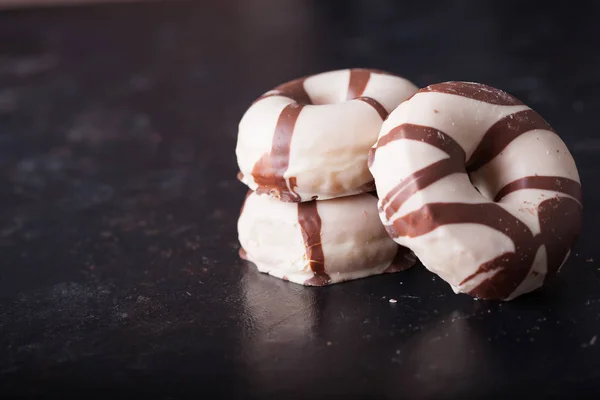 Gestreifte Donuts auf dunklem Holztisch im Studio — Stockfoto