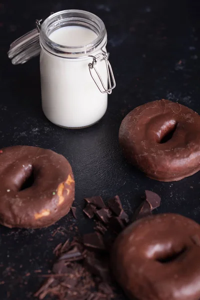 Chocolade donuts in de buurt van fles melk en chocolade kruimels. — Stockfoto