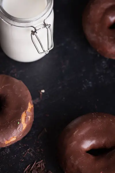 Chocolade donuts in de buurt van fles melk en chocolade kruimels. — Stockfoto