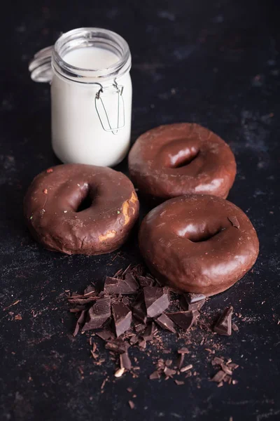 Chocolade donuts in de buurt van fles melk en chocolade kruimels. — Stockfoto