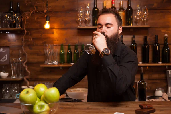 Joven camarero tatuado con gran barba degustando una copa de vino . —  Fotos de Stock