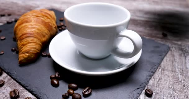 Verser une tasse de café pour servir avec un savoureux croissant — Video