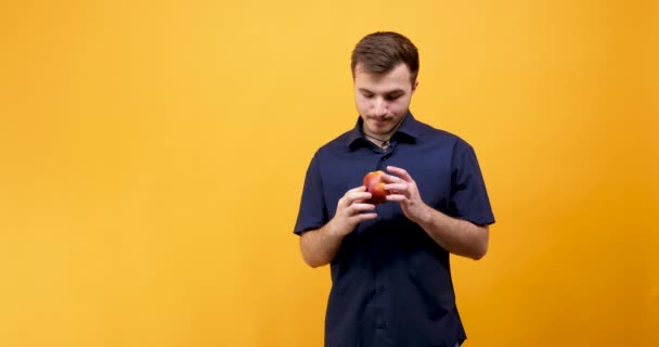 Young handsome male eating a red apple — Stock Video