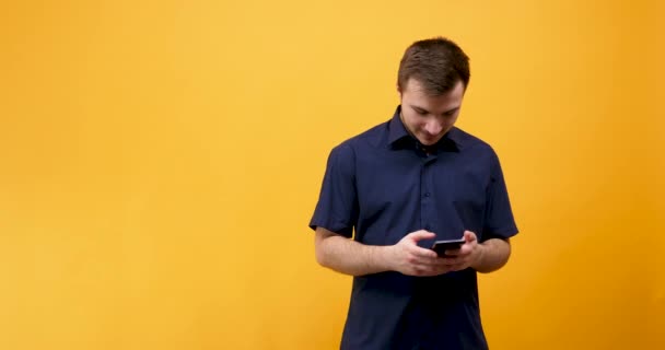 Gelukkig jonge man kijkend naar zijn telefoon — Stockvideo