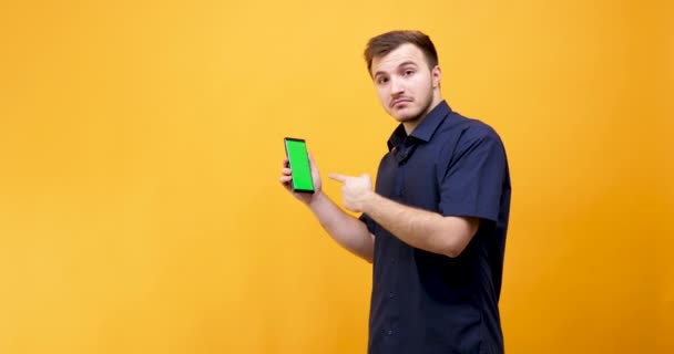 Caucásico joven sosteniendo un teléfono con pantalla verde en él — Vídeo de stock