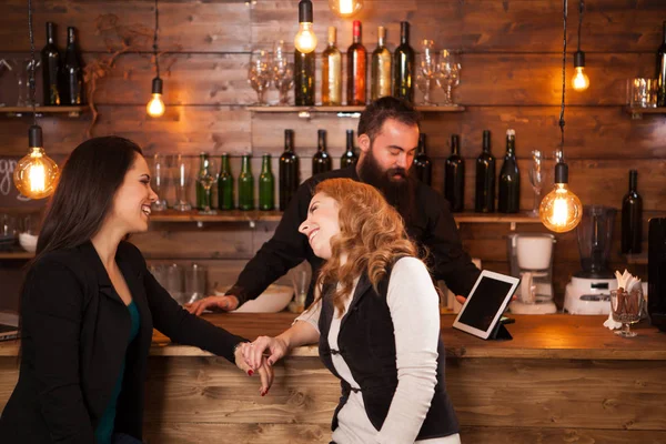 Amigos felices interactuando en el mostrador de un bar — Foto de Stock